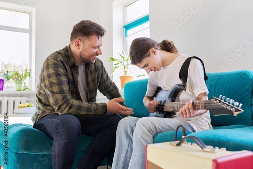 Father teaches his teenage son to play the electric guitar