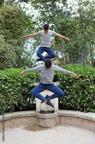 Two young twin brothers jumping and dancing contemporary ballet in the park with urban costume.