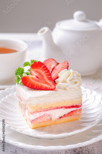 Homemade Strawberry Shortcake with Strawberry Sauce Filling on White Dish and Hot Tea Serve. Concept of having morning or afternoon tea with cake.