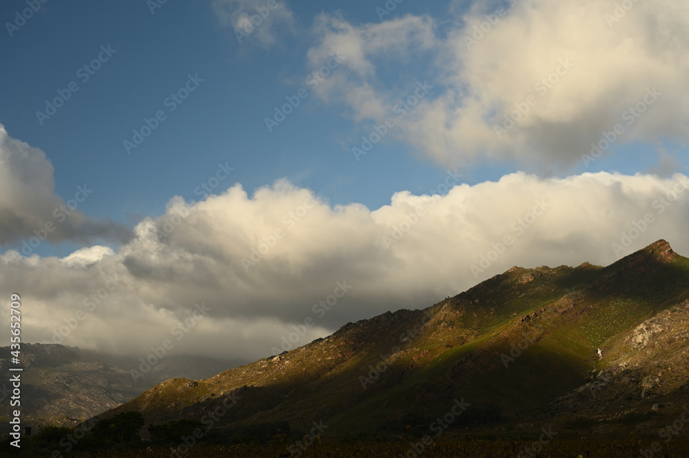 Clouds hanging over the rugged mountains of Du Toitskloof with a bright sun shining on it Clouds hanging over the rugged mountains of Du Toitskloof with a bright sun shining on it