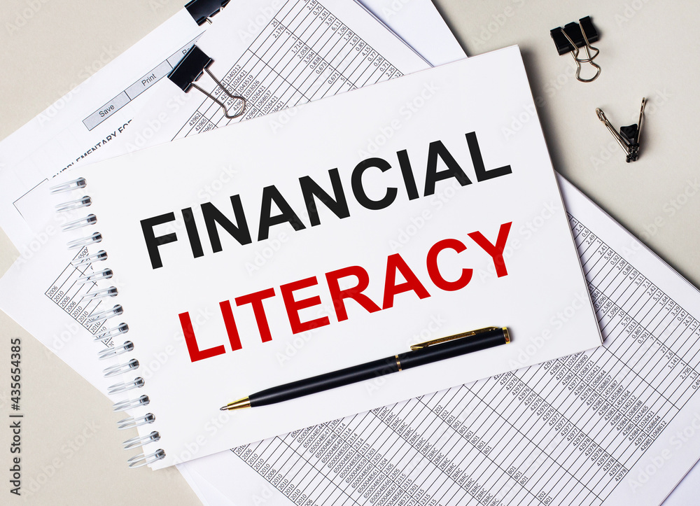 On the desktop there are documents, pen, black paper clips and a notebook with the text FINANCIAL LITERACY. Business concept On the desktop there are documents, pen, black paper clips and a notebook with the text FINANCIAL LITERACY. Business concept