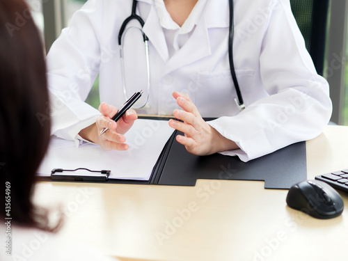 A close-up of the hand of a female doctor or nurse holding a pen is talking or explaining information or something for a patient...