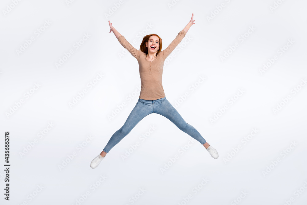 Full length photo of charming pretty redhair woman beige shirt jumping high like star smiling isolated white color background
