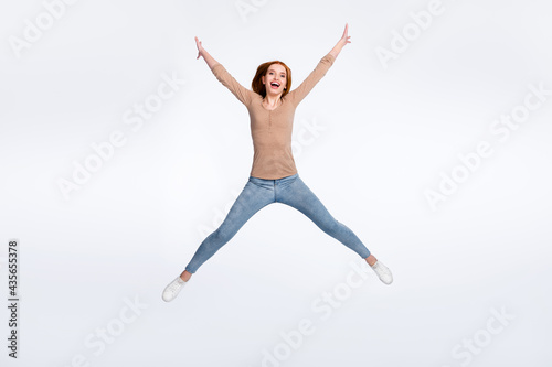 Full length photo of charming pretty redhair woman beige shirt jumping high like star smiling isolated white color background