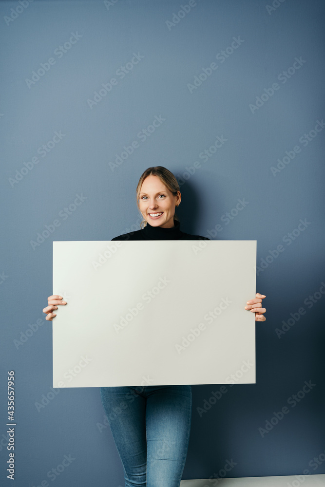 Happy friendly amiling young woman holding a blank white placard Happy friendly amiling young woman holding a blank white placard