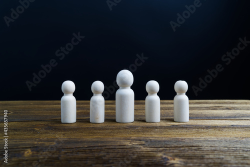 Unpainted wooden doll as boss and employee mock up for create symbol or emotion place align as row on wood plate with black background and copy space. Business and finance concept teamwork successful.