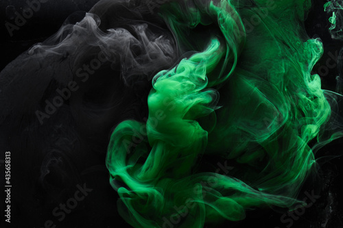 Abstract dance of green and black smoke under water, paint in water, colorful cloud in motion. Fluid art wallpaper, liquid vibrant colors
