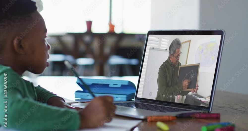 African american boy sitting at desk using laptop having online school lesson African american boy sitting at desk using laptop having online school lesson