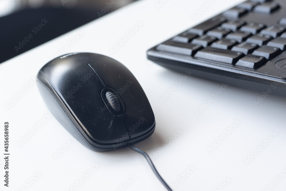 Black dirty mouse on the office desk with keyboard Black dirty mouse on the office desk with keyboard