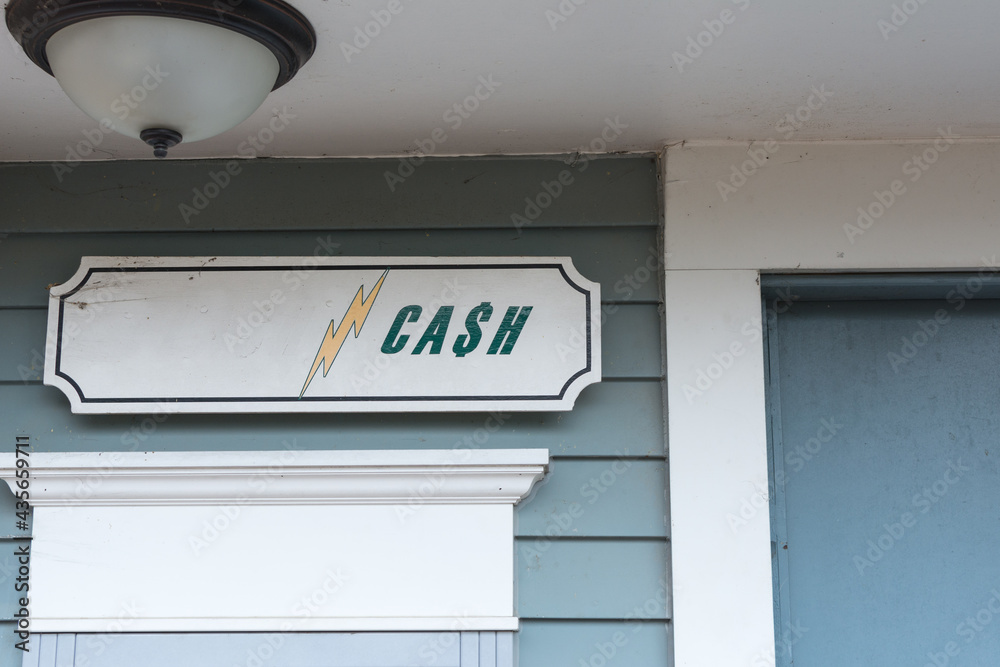 Abandoned cash ATM machine with part of signage painted over; lightning bolt and cash sign