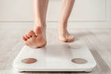 Woman foot takes a step onto a smart scale that makes bioelectric impedance analysis, BIA, body fat measurements. 