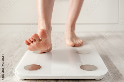 Woman foot takes a step onto a smart scale that makes bioelectric impedance analysis, BIA, body fat measurements. 