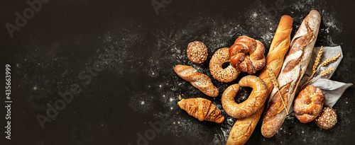 Bakery - bread rolls, baguette, bagel, sweet bun and croissant on black background