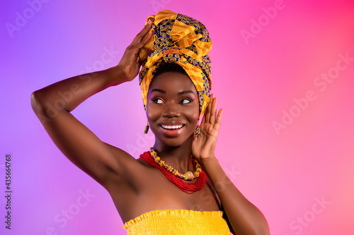 Photo of young afro american woman look empty space smile touch tribal clothes isolated on vibrant background photo