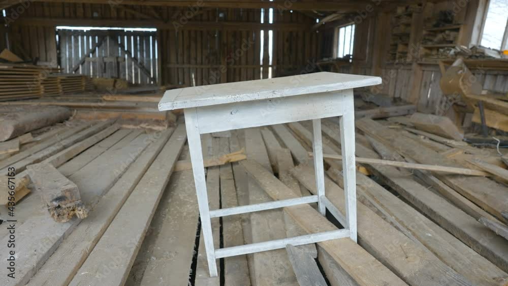 A white table inside the wooden storage house with lots of planks and dust inside A white table inside the wooden storage house with lots of planks and dust inside