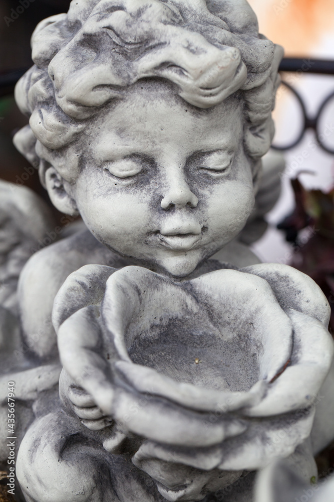 Kleine Engel Figur aus Stein mit einer Rose in der Hand