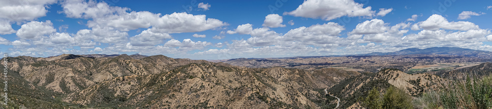 Los Padres National Forest, CA, USA - May 21, 2021: Wide panorama shot of eastern part under heavy blue cloudscape with road 33 cutting through. Green trees and shrub.