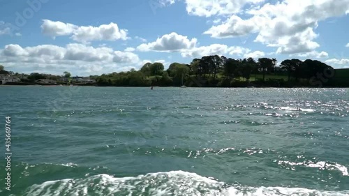 Slow motion footage taken from ferry ride on Salcombe estuary in Devon. Bright sunny day with blue sky and waves moving across the water
