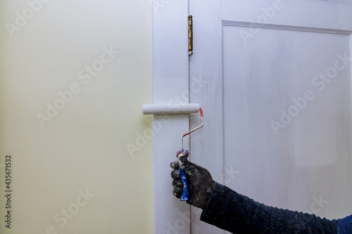 Contractor painter updating colors of painting doors molding trim using hand roller painting