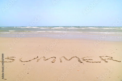 Text "SUMMER" with the waves beat at the beach and blue sky in the summer morning. Nature and holiday concept.