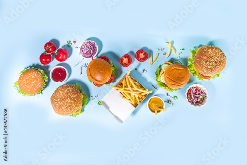 Fastfood, burger party concept. Various delicious burgers set with french fries and sauces on bright blue background flatlay top view copy space