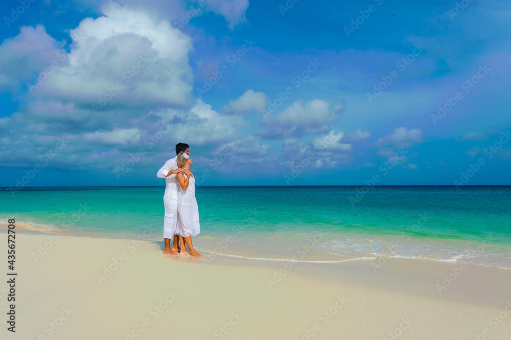 Young couple walking on the beach, in white outfits Young couple walking on the beach, in white outfits