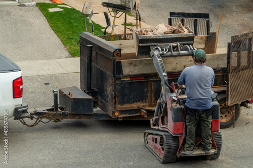 The tractor driver loads stones from the construction site into the trailer.