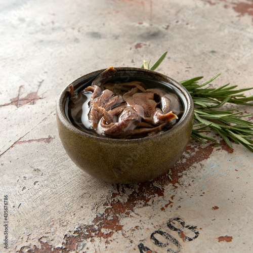 a bowl of anchovies in oil and a sprig of rosemary on the table photo