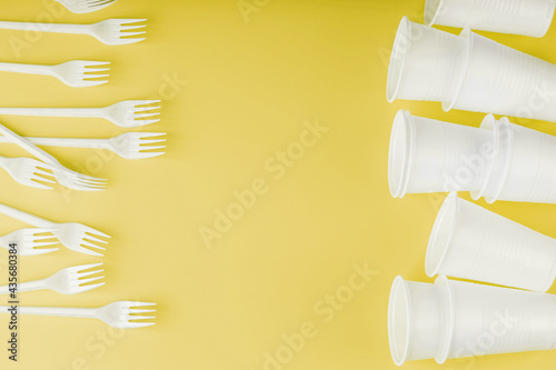 Plastic tableware on a yellow background with free space.