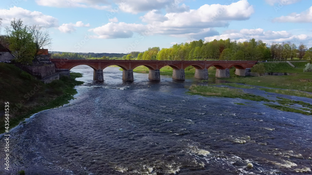 Long Old Brick Bridge, Kuldiga, Latvia Across the Venta River. Captured From Above. The Widest Waterfall in Europe in Background