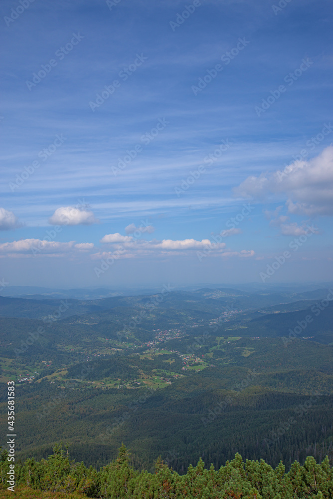 Vertical view from top of the Babia Góra mountain, with dramatic sky and clouds above and village and little houses at the bottom visible. Located near Zawoja in Beskid Żywiecki region. 