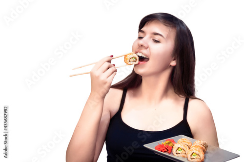 Young girl on an isolated background eats sushi