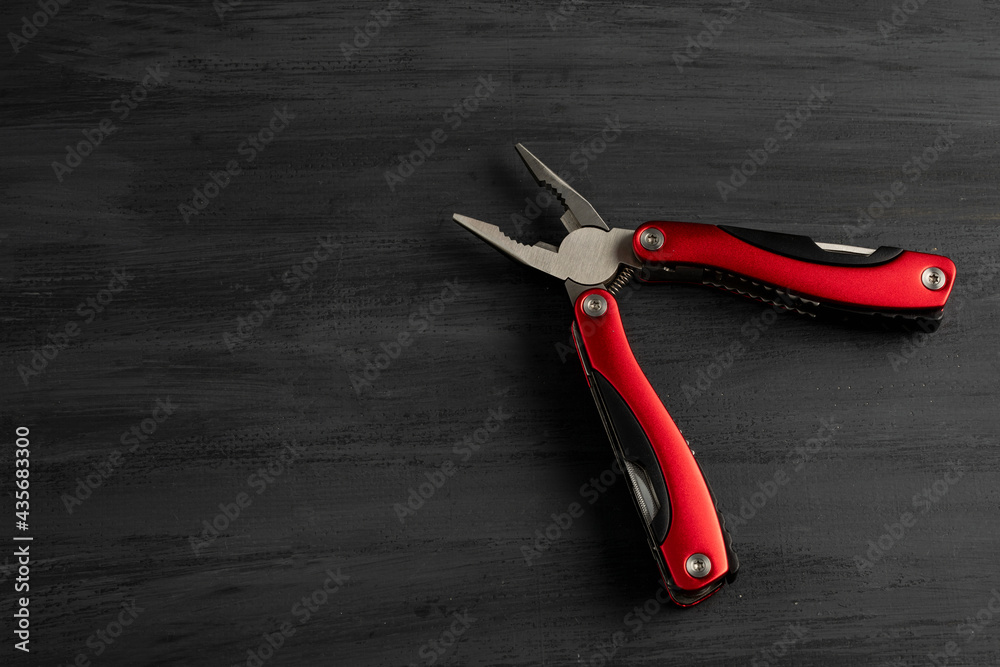 Pinzas multiusos de color rojo con un fondo gris. Herramienta de mano multiusos Pinzas multiusos de color rojo con un fondo gris. Herramienta de mano multiusos