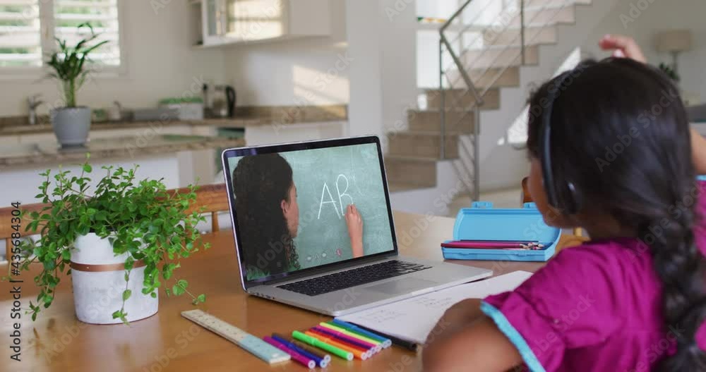 African american girl doing homework while having a video call with female teacher on laptop at home African american girl doing homework while having a video call with female teacher on laptop at home