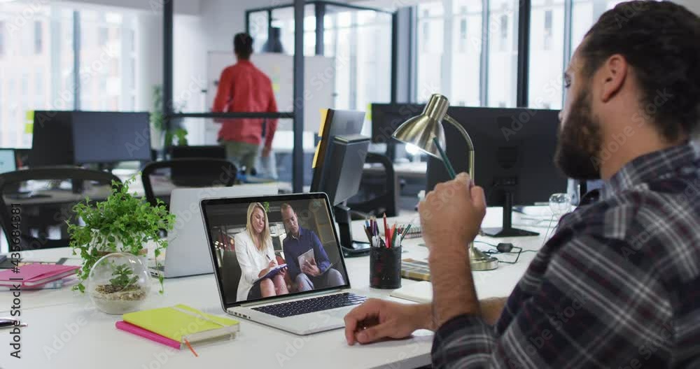Middle eastern man having a video call with male and female colleagues on laptop at office Middle eastern man having a video call with male and female colleagues on laptop at office
