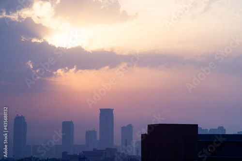 cloudy dusk dawn shot with the sun hidden and fog obscured sky scrapers multi story buildings of cityscape of gurgaon, mumbai, bangalore during the monsoons in India