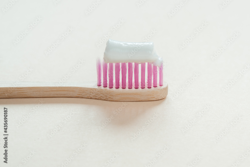 Pink bamboo toothbrush with tooth paste on it close-up, dental care with zero waste concept, sustainable lifestyle Pink bamboo toothbrush with tooth paste on it close-up, dental care with zero waste concept, sustainable lifestyle