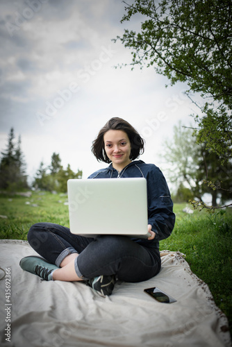 a woman works on a laptop while sitting in nature during the coronavirus pandemic. High quality photo