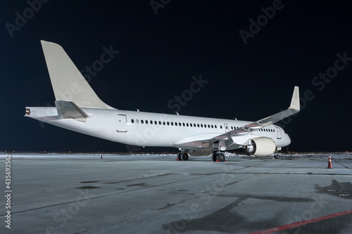 Modern white passenger airplane on the night airport apron