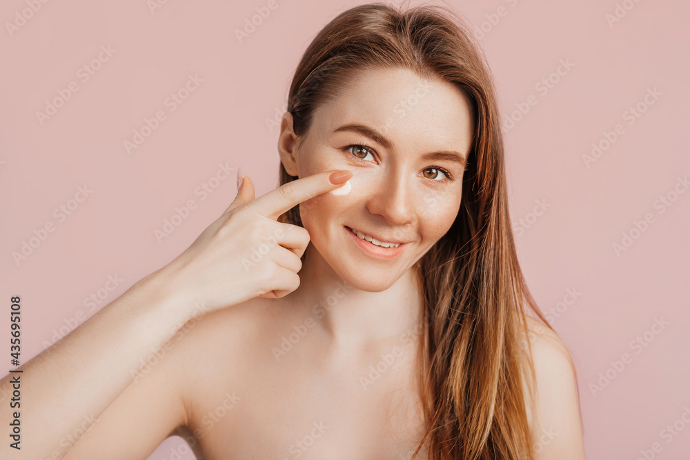 Girl make face beauty masks. Anti-wrinkle cream for the freshness of the skin around the eyes. Woman take care of youthful skin. Model laughing and having fun in spa on pink background Girl make face beauty masks. Anti-wrinkle cream for the freshness of the skin around the eyes. Woman take care of youthful skin. Model laughing and having fun in spa on pink background