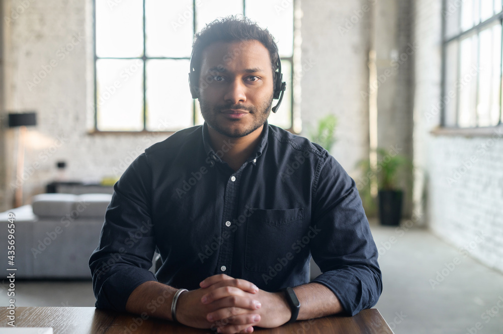 Portrait of serious indian guy wearing wireless headset looks at the  camera, video connect with multiracial colleague, video chat with hindu guy  in headphones, webcam view, video call concept Photos | Adobe