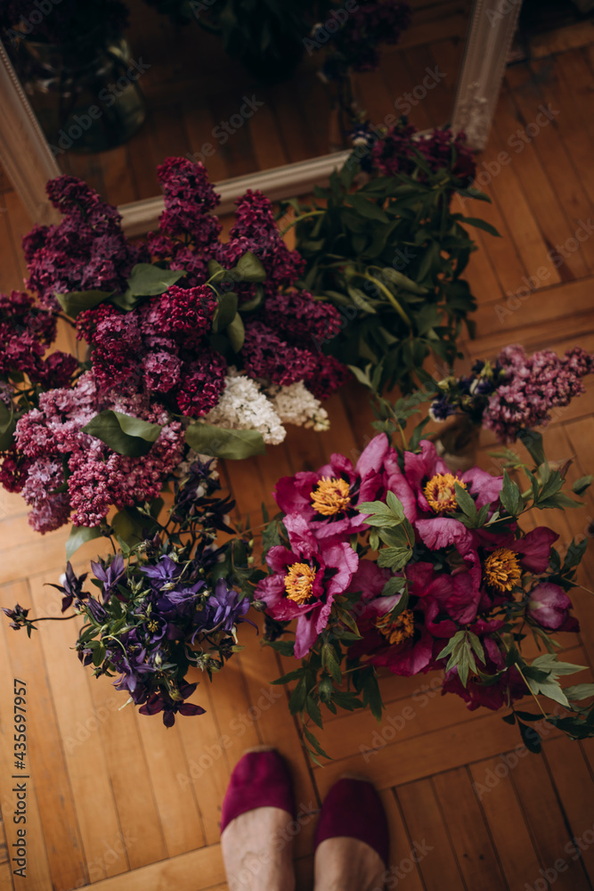 bright fresh beautiful bouquets on the parquet floor top view. female feet and flowers. bouquet of lilac and tree peonies top view. bright fresh beautiful bouquets on the parquet floor top view. female feet and flowers. bouquet of lilac and tree peonies top view.