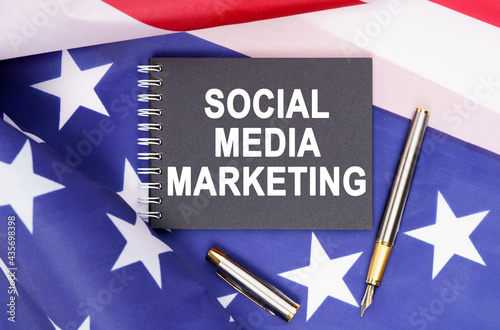 On the table is an American flag, a pen and a notebook with the inscription - SOCIAL MEDIA MARKETING