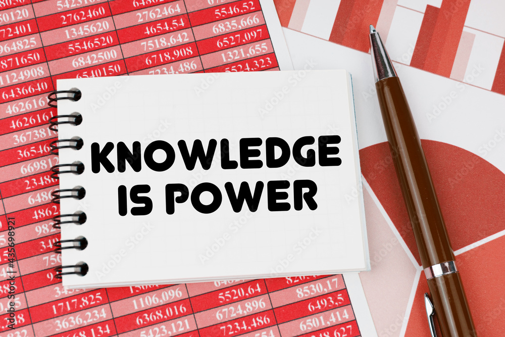 On financial documents and charts there is a notebook with the inscription - KNOWLEDGE IS POWER On financial documents and charts there is a notebook with the inscription - KNOWLEDGE IS POWER