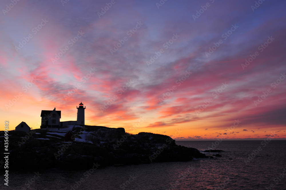 Sunrise and moon set at the Cape Neddick lighthouse on the Maine coast