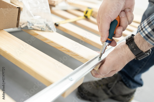 Hands Assembling a bed frame using a screwdriver