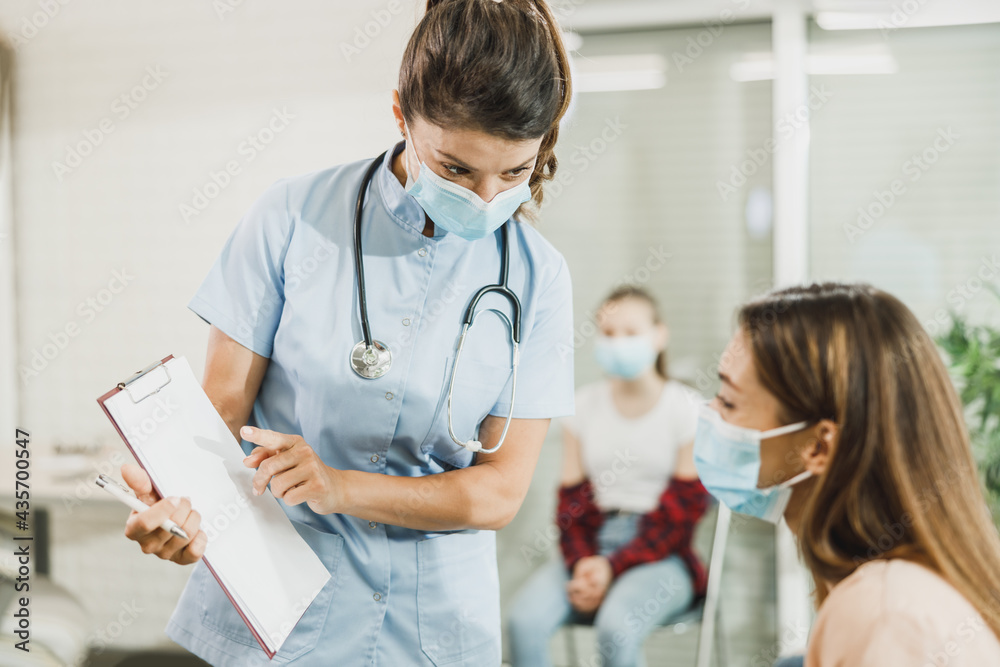 Woman With Protective Mask Talking To Nurse At Waiting Room
