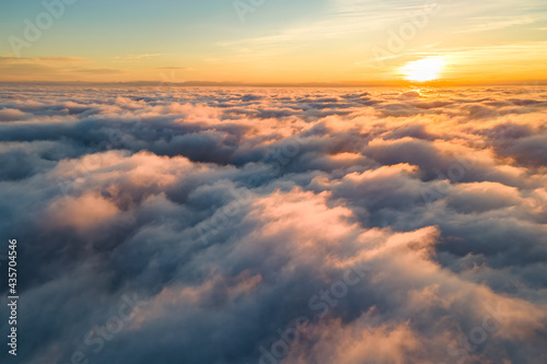 Canvas Print Aerial view of bright yellow sunset over white dense clouds with blue sky overhead