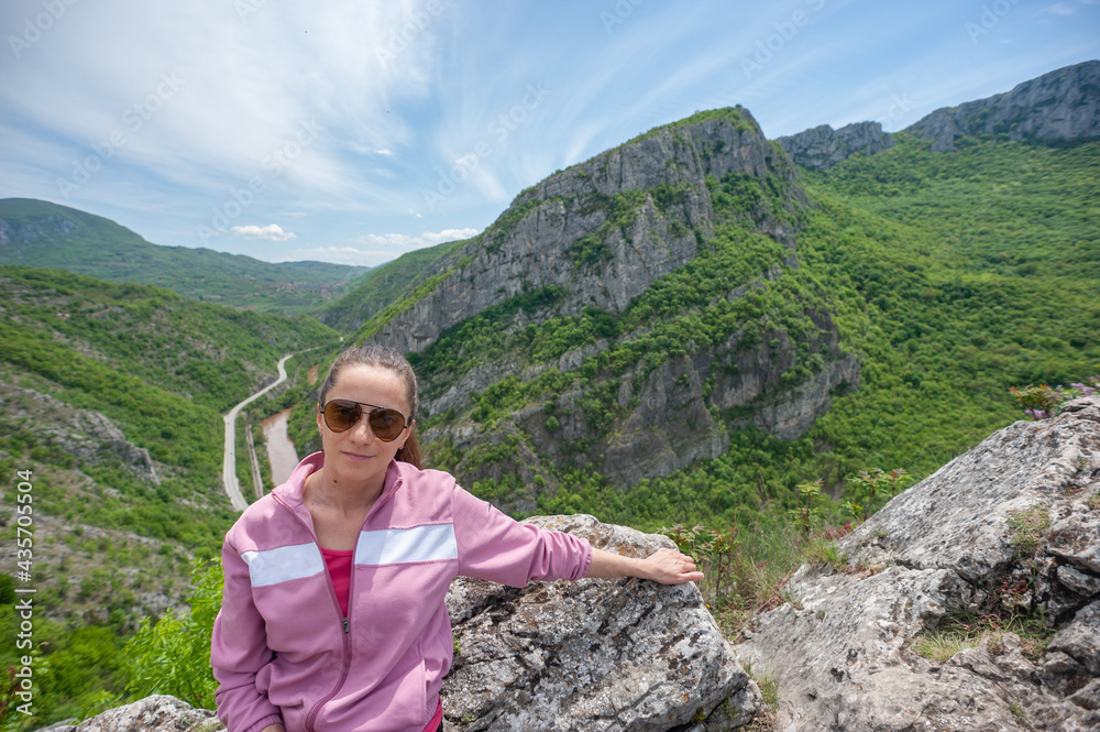 A young woman is sitting on the top of the canyon in Sicevo (Sićevo, Sićevačka klisura)