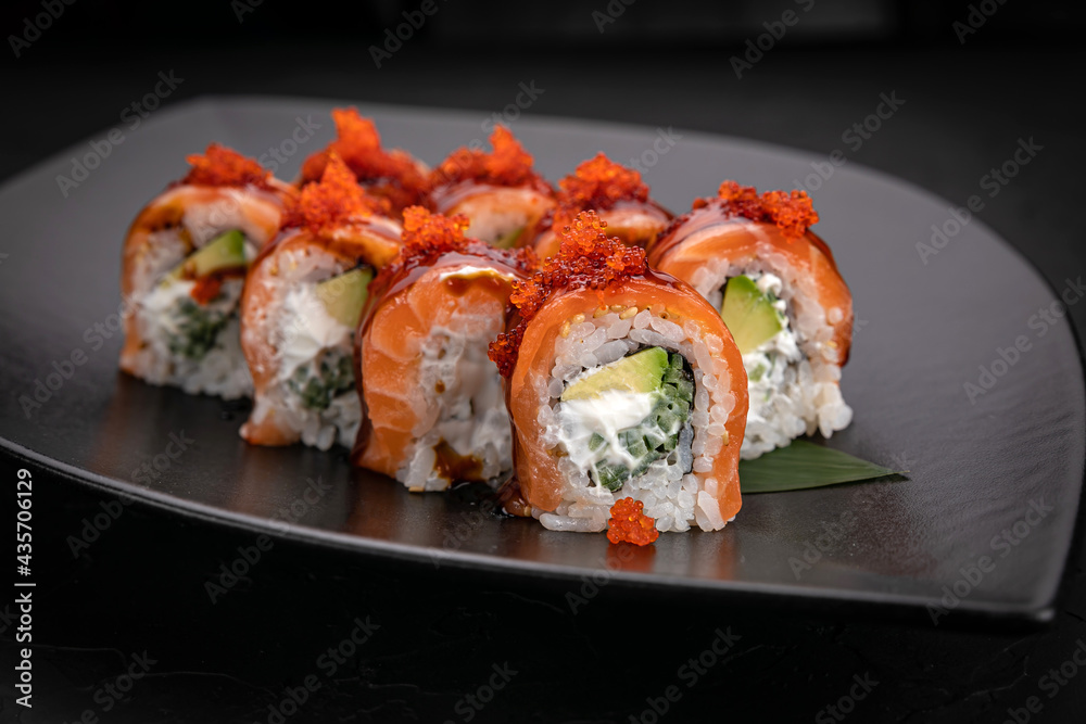 Japanese cuisine. Rolls on a black plate on a wooden table
Japanese cuisine. Rolls on a black plate on a wooden table